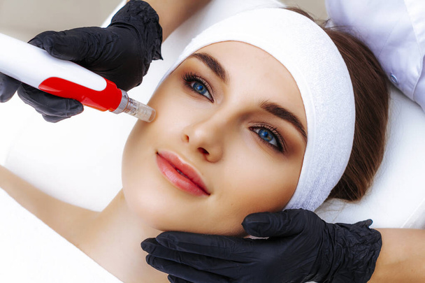 Woman getting Radiofrequency face lifting. Hardware facial cosmetology. RF lifting photo. - 写真・画像
