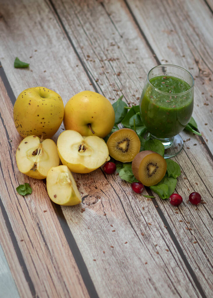 Un verre de kiwi, d'épinards et de smoothie aux pommes. Une boisson santé. Pommes, graines de lin, épinards, kiwi, bananes se trouvent à proximité. - Photo, image