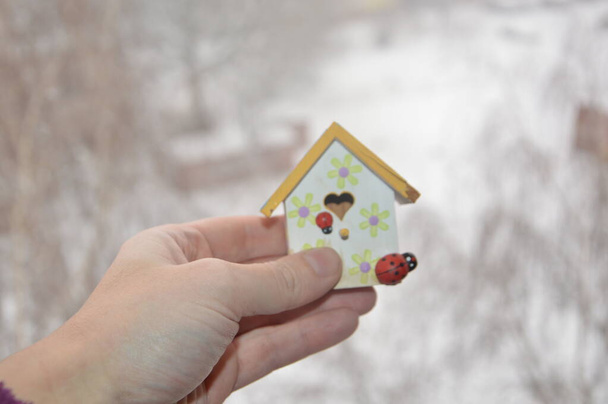 Malý domek stojí na okenním rámu na pozadí zimy - Fotografie, Obrázek