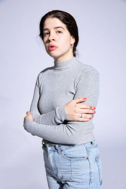 Proud girl model in roll neck with folded arms isolated on grey - Photo, Image