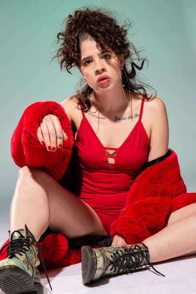 White girl model in red clothes sitting isolated on green - Photo, Image