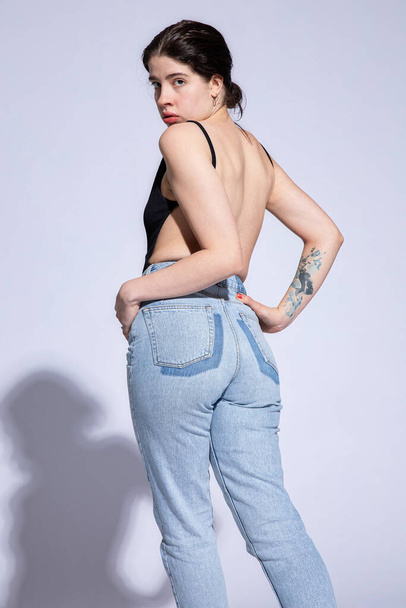Young white woman in jeans isolated on grey - Foto, Imagem
