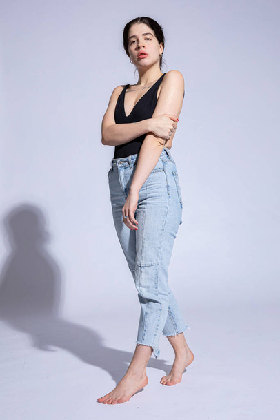 Serious white girl in light blue jeans isolated on grey - Photo, Image