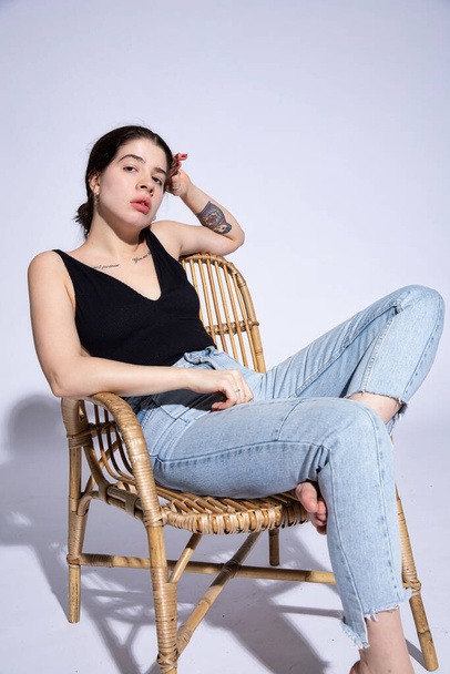 White sitting girl in jeans and black top isolated on grey - Fotó, kép