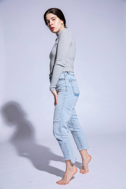 White young woman stand in jeans isolated on grey - 写真・画像