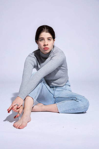 White girl sits on the floor with big lips isolated on grey - Foto, Imagen