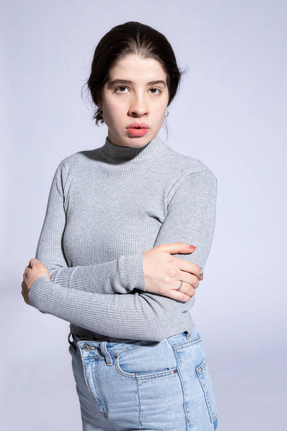 Serious girl model in roll neck with folded arms isolated on grey - Foto, afbeelding