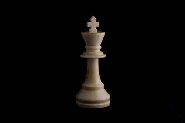 один боковой свет на белой шахматной фигуре короля в черном фоне - Фото, изображение