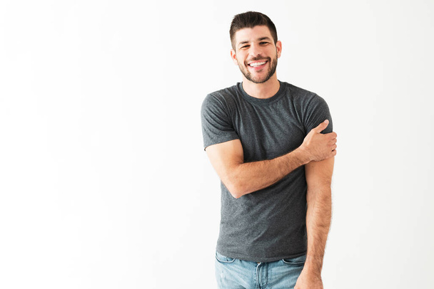 Retrato de un joven hispano guapo luciendo feliz y riéndose con alguien frente a un fondo blanco - Foto, imagen