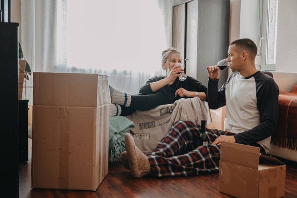 Moving Day, new home, Valentines Day, unpacking boxes, newlyweds concept. Couple Celebrating Moving Into New Home and have fun With wine - 写真・画像