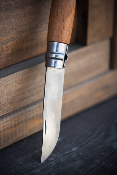 folding knife with wooden handle on wooden background - Fotó, kép