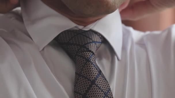 Ο επιχειρηματίας βάζει γραβάτα ως προετοιμασία για το πρωί της εργάσιμης ημέρας. Κώδικας ενδυμασίας για κάθε μέρα. Το κλασικό στυλ ενός μοντέρνου άντρα. Κοντινό πλάνο - Πλάνα, βίντεο