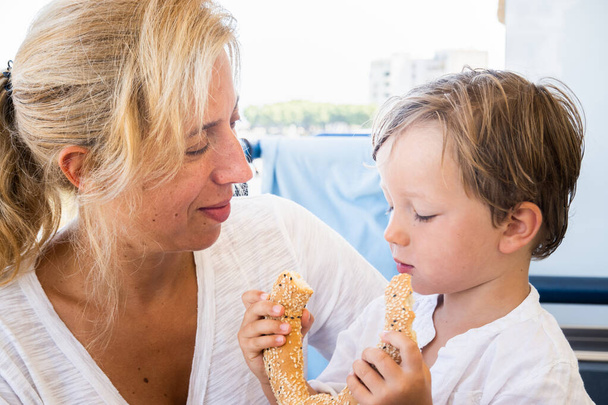 Niño sosteniendo pretzel mientras la madre lo mira - Foto, Imagen