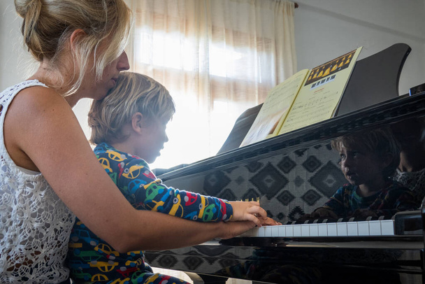 Figlio seduto sul grembo materno a suonare il pianoforte - Foto, immagini
