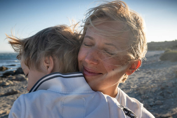 Крупный план сына и матери, обнимающих друг друга на пляже - Фото, изображение