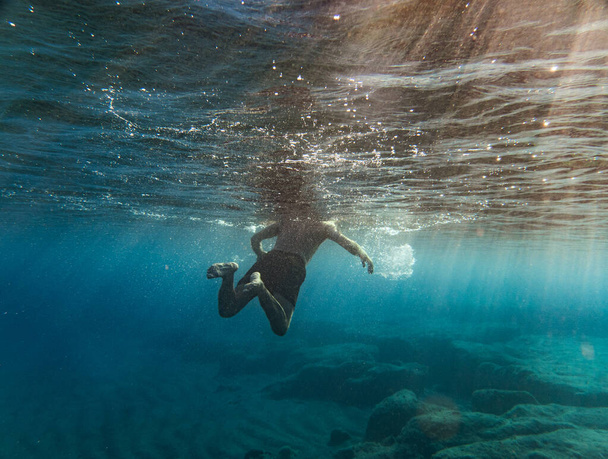Rückansicht eines Jungen, der im Meer schwimmt - Foto, Bild