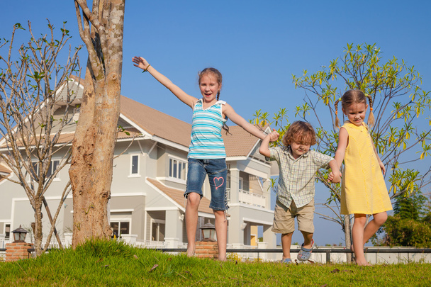 two happy  girls and little boy standing near the house - 写真・画像
