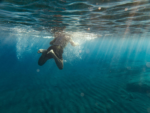 Вид сзади на купание мальчика в море - Фото, изображение
