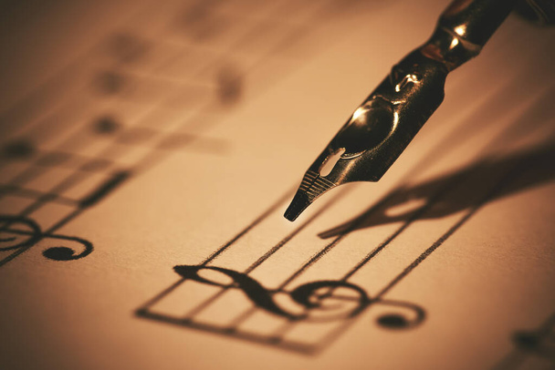 zenei jegyzeteket ír papírra tollal és tintával. zeneoktatás. közelkép - Fotó, kép