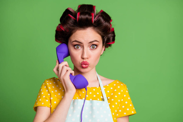 Photo of pretty retro girl call telephone cord send air kiss helpline landline service center wear yellow dotted dress skirt hair rollers isolated over green color background - Foto, Imagem