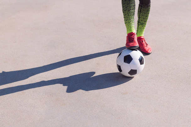 detail of a footballer feet with one foot on the ball in a concrete soccer field, concept of healthy lifestyle and urban sport in the city, copy space for text - Фото, зображення