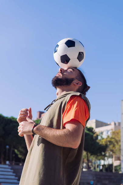 pionowy portret piłkarza grającego równoważącego piłkę na głowie, koncepcja zdrowego stylu życia i sportów miejskich w mieście, kopiowanie miejsca na tekst - Zdjęcie, obraz