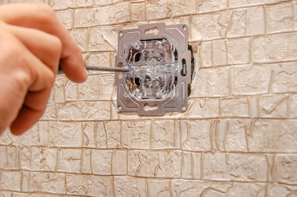 Elektryk instaluje przełącznik na ścianie ze śrubokrętem zamykającym - Zdjęcie, obraz