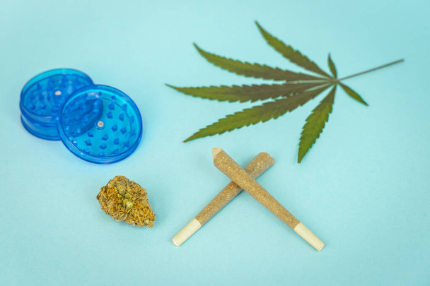 Pre-rolled CBD medical marijuana and hemp leaves on blue cyan background. Organic and natural hemp-based cosmetic and beauty products. Medical cannabis concept. Still life. - Fotó, kép