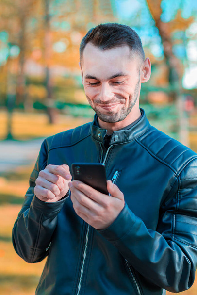 Handsome Guy Using Smartphone at Autumn Park - Valokuva, kuva