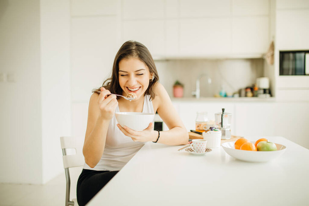 Young smiling woman eating cereal.Healthy breakfast.Starting your day.Dieting,fitness andmental health care.Positive energy and emotion.Productivity,happiness,enjoyment at home.Morning ritual - Fotoğraf, Görsel