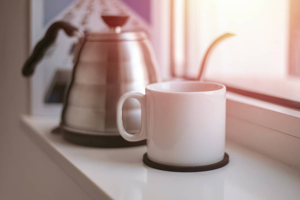 white cup of tea with a teapot is standing at the window. Mockup. Copy space. Tinting - Fotó, kép