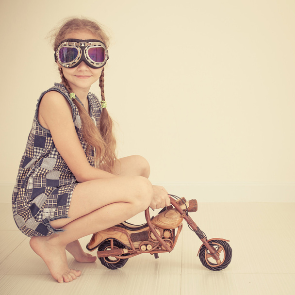 little girl in glasses on toy motorcycle - Fotó, kép