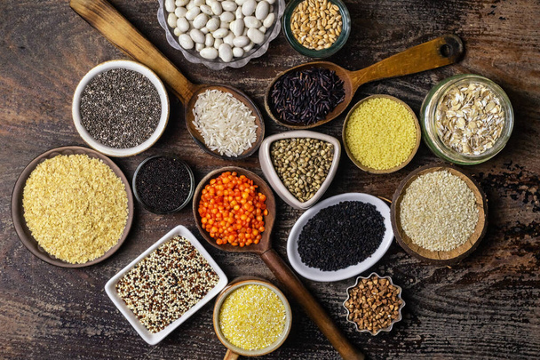 Food background of various cereals and grains in plates on a wooden table, top view - Photo, Image