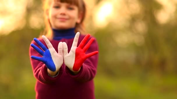 Freedom France concept. Cute child forming flying bird gesture with painted in France colors hands at bright sunset. - Footage, Video