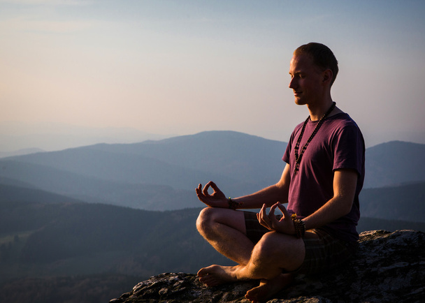 Homem meditando em uma rocha
 - Foto, Imagem