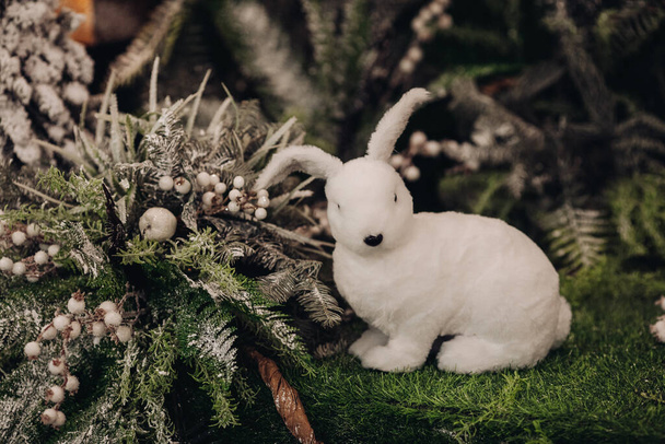 foto van mooi wit konijntje tussen een boom met veel sneeuw erop - Foto, afbeelding