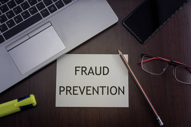 Fraud prevention card. Top view of office table desktop background with laptop, phone, glasses and pencil with card with inscription fraud prevention.  Security concept. - Photo, Image