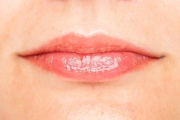 Sexy lips. Macro of the female part of the face. Beauty pink lips makeup detail. Lipstick and lip gloss. lip correction - 写真・画像