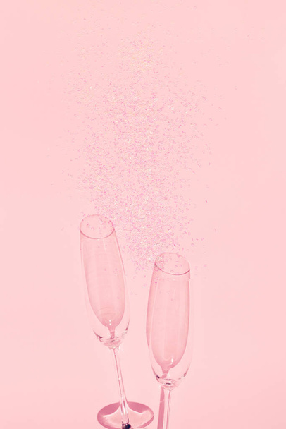 Dos copas de champán chrystal con confeti en forma de corazón sobre fondo rosa pastel. Estilo mínimo. Concepto de celebración. Tema Día de San Valentín. Fondo festivo y festivo. Acostado. Vista superior. - Foto, imagen