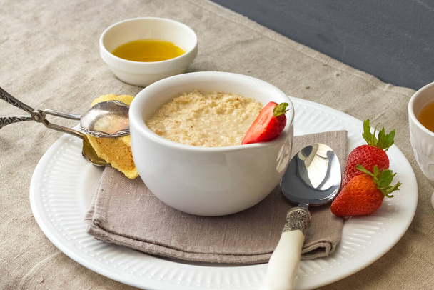 delicious and healthy breakfast of oatmeal with fresh strawberries. Rustic style - Фото, изображение