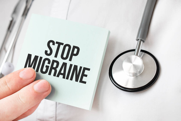 Doctor holding card in hands and pointing the word STOP MIGRAINE - Foto, Imagen