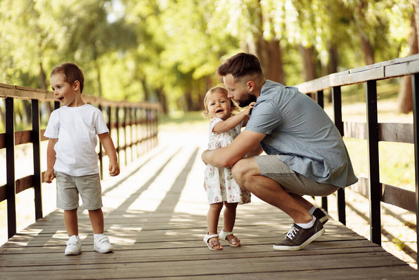 公園でリラックスしている子供たちと幸せな若い父親 - 写真・画像