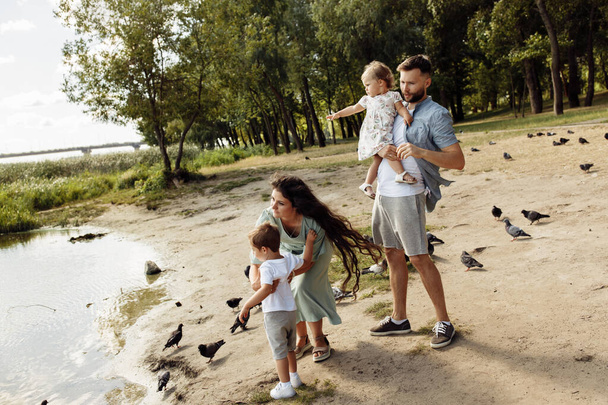 Happy young family with children watching  birds   in the park - 写真・画像