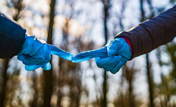 Mother`s and son`s hands in rubber medical gloves. Parental relationships between people. Protection, isolation and distance during the Covid-19 coronavirus pandemic. - Photo, image