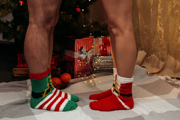 Male and female feet in winter socks touching each other. - 写真・画像