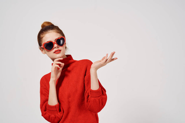 Modisches Frauenmodel in rotem Pullover und Sonnenbrille gestikuliert mit den Händen - Foto, Bild
