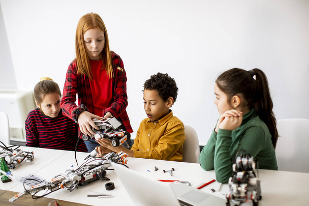 A boldog gyerekek csoportja elektromos játékokat és robotokat programoz a robotika tanteremben - Fotó, kép