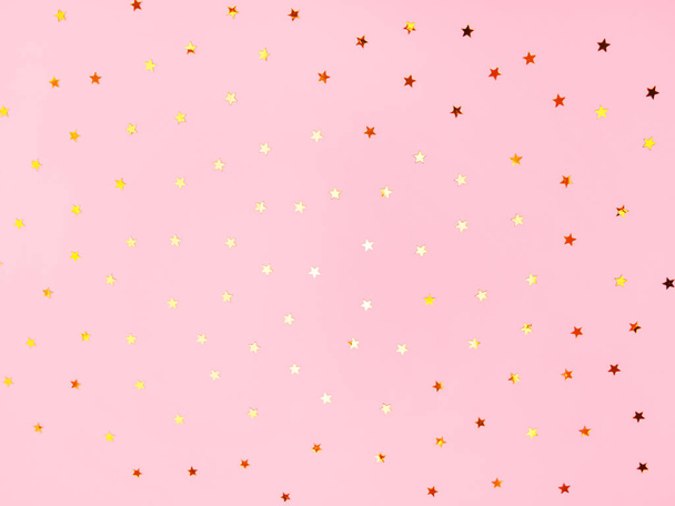 ピンクのパステルカラーのファッションを背景にゴールドの星が輝きます。コンフェッティが落ちる。プロジェクトのフェスティバル背景. - 写真・画像