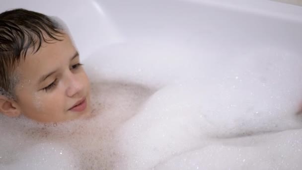 Baños de niño en el baño con espuma, Juega con burbujas de espuma jabonosa, Niño feliz - Metraje, vídeo