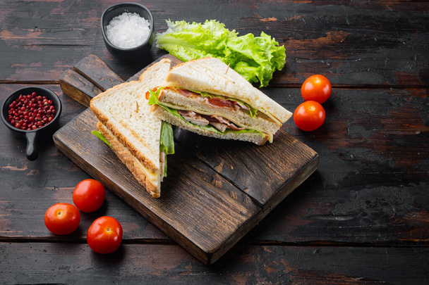 Club sanduíche panini com presunto, tomate fresco, queijo, em fundo de madeira escura - Foto, Imagem